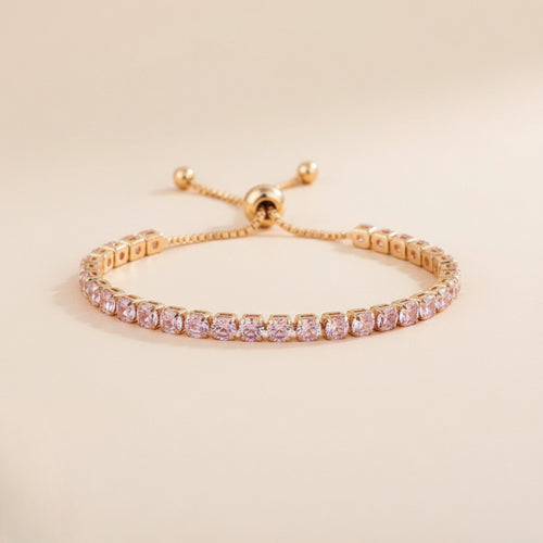 Gold bracelet with pink gemstones on a beige background