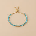 Turquoise beaded bracelet with gold clasp on beige background