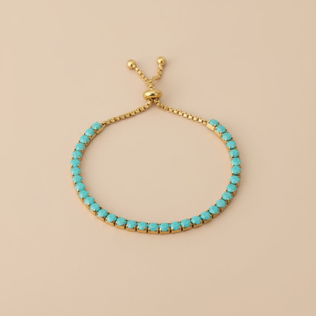 Turquoise beaded bracelet with gold clasp on beige background