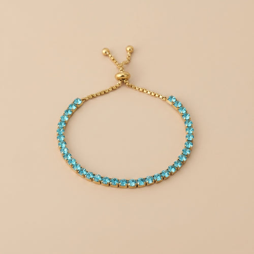 Turquoise beaded bracelet with gold clasp on beige background