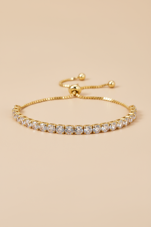 Gold bracelet with clear stones on a beige background