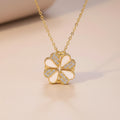 Gold necklace with a heart shaped clover pendant on a beige background
