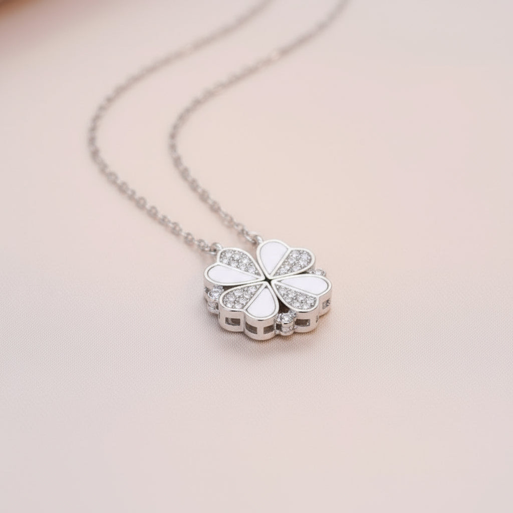 Silver necklace with a heart shaped pendant on a light pink background
