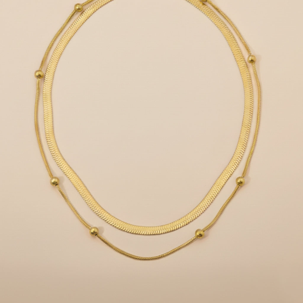 Gold double layer necklace on a beige background