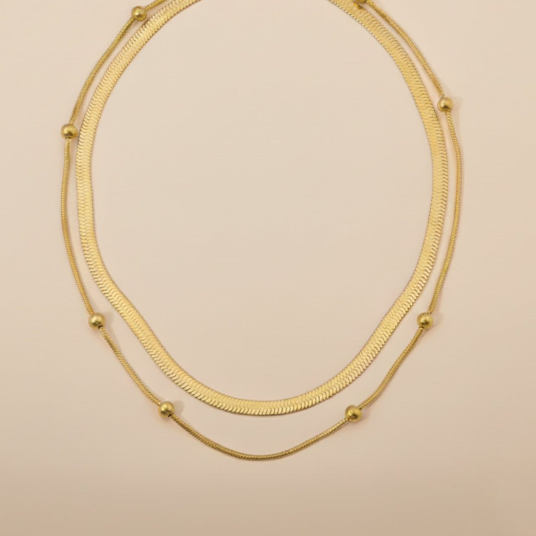 Gold double layer necklace on a beige background