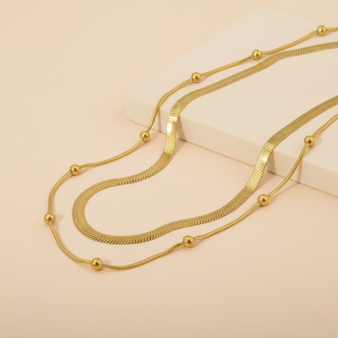 Gold double layer necklace on a beige background