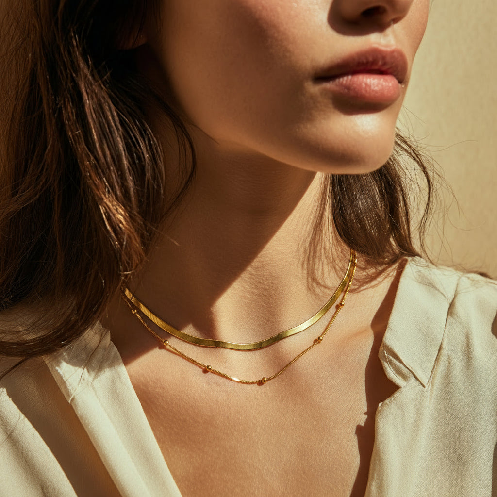 Close-up of a woman wearing a gold necklace against a neutral background