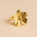 Gold flower-shaped ring on a beige background