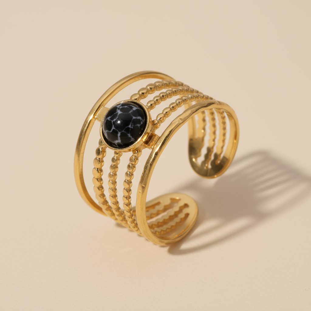 Gold bracelet with a black stone on a beige background