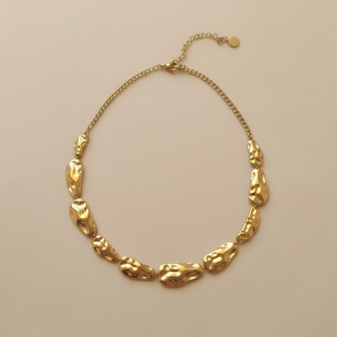 Gold necklace with unique links on a beige background