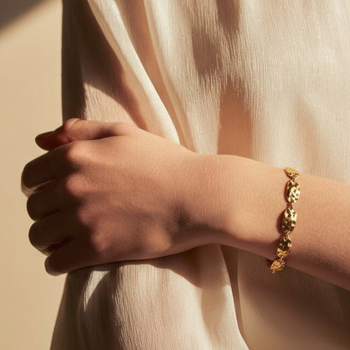 Gold bracelet on a wrist with a neutral background