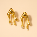 Gold earrings with pearl drops on a beige background
