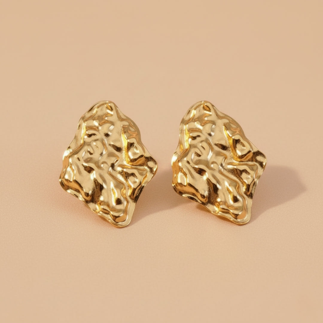 Gold earrings on a beige background