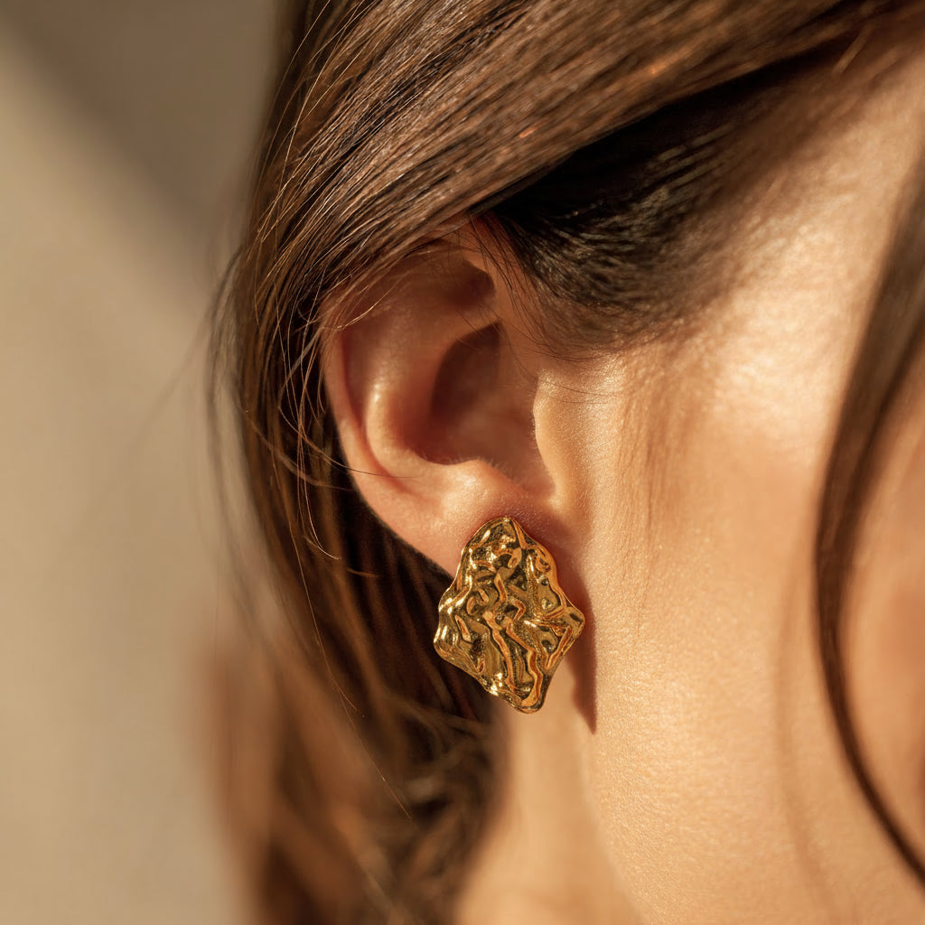 Gold earring worn by a person with a neutral background