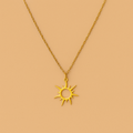 Gold sun-shaped pendant necklace on a beige background