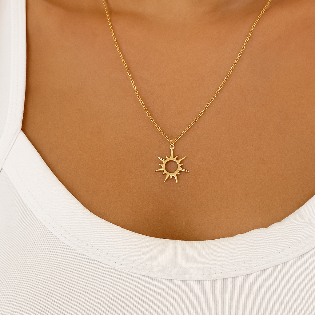 Gold necklace with a sun pendant worn by a person