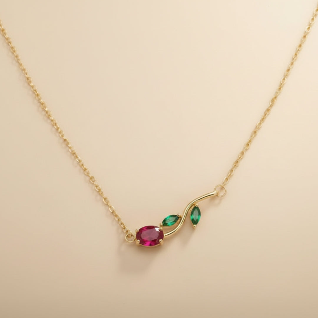 Gold necklace with red and green gemstones on a beige background