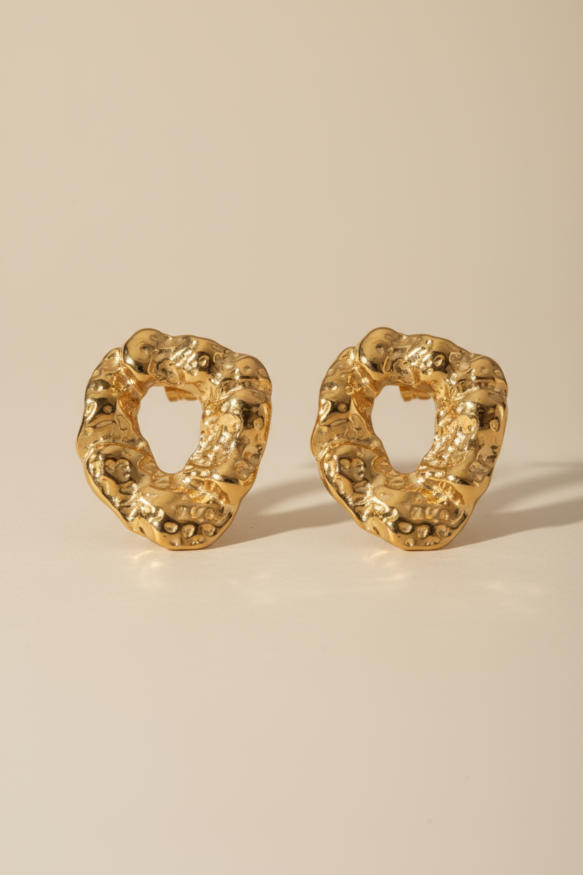 Pair of gold textured hoop earrings on a beige background