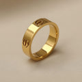 Gold ring with engraved symbols on a beige background