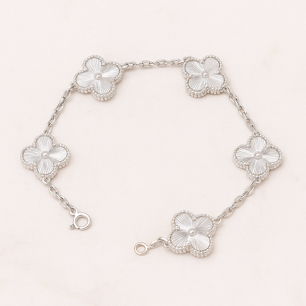 Silver bracelet with clover designs on a light pink background