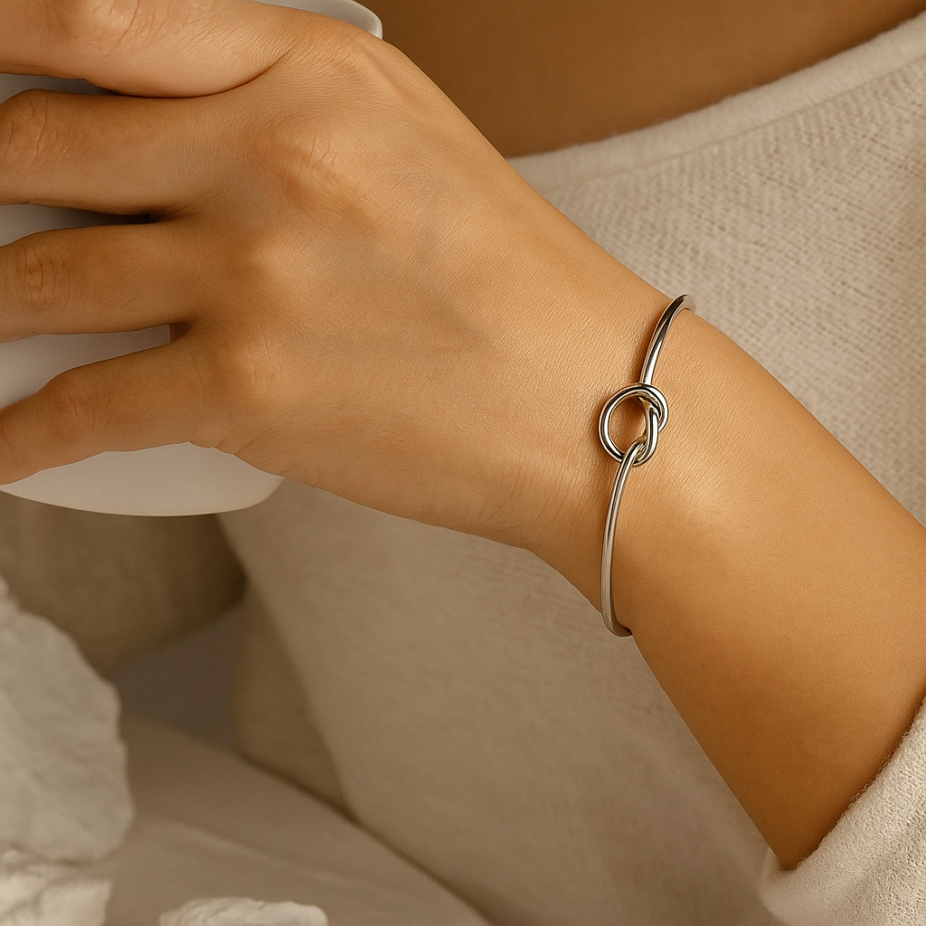 Close-up of a hand wearing a silver bracelet with a knot design.
