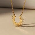 Gold sun-shaped pendant necklace on a beige background