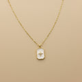 Gold necklace with a star pendant on a beige background