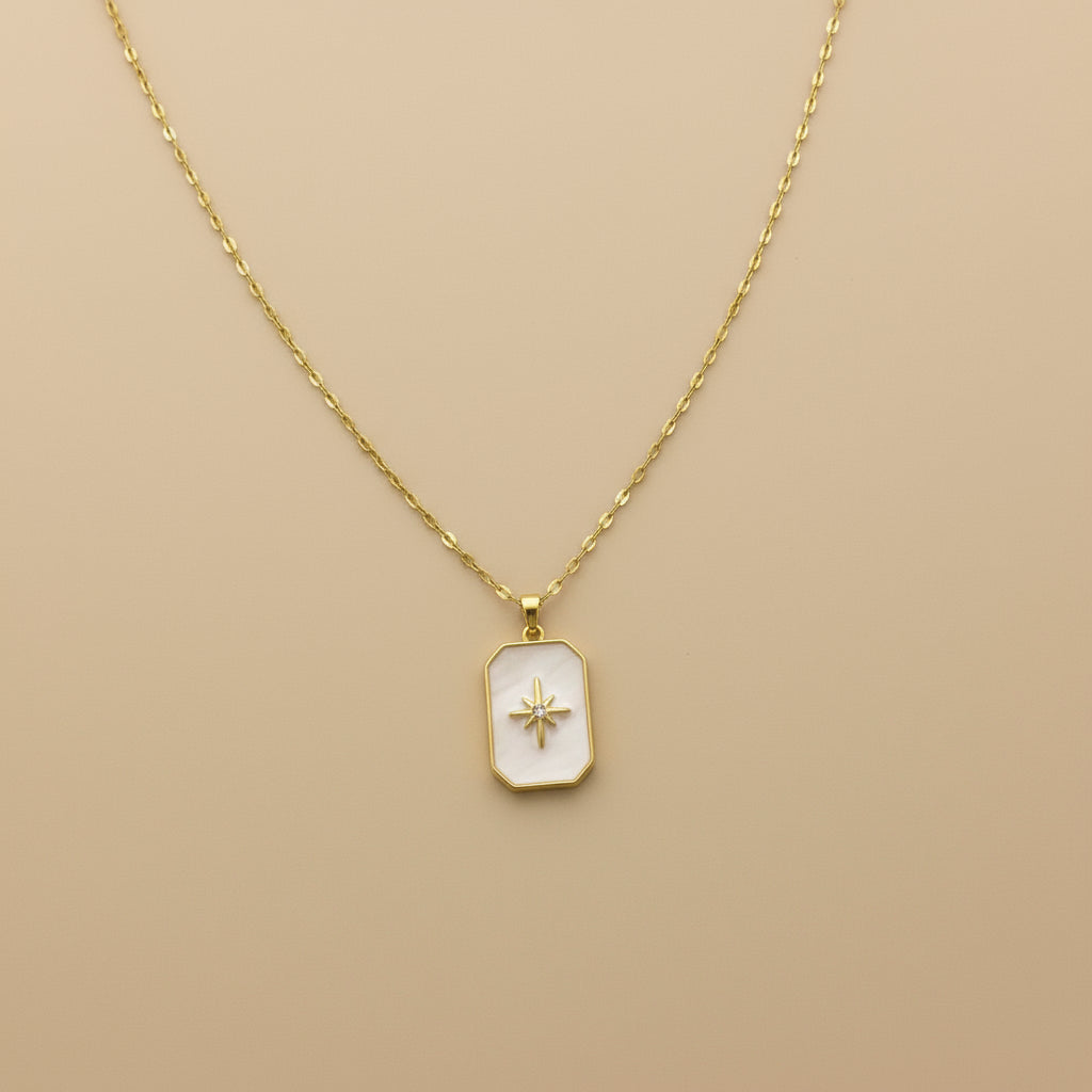 Gold necklace with a star pendant on a beige background