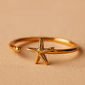 Gold starfish ring on a beige background