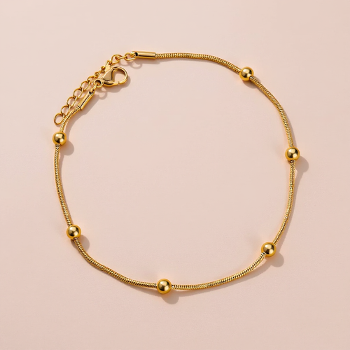 Gold Anklet with gold beads on a beige background