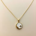 Gold necklace with a round pendant on a beige background
