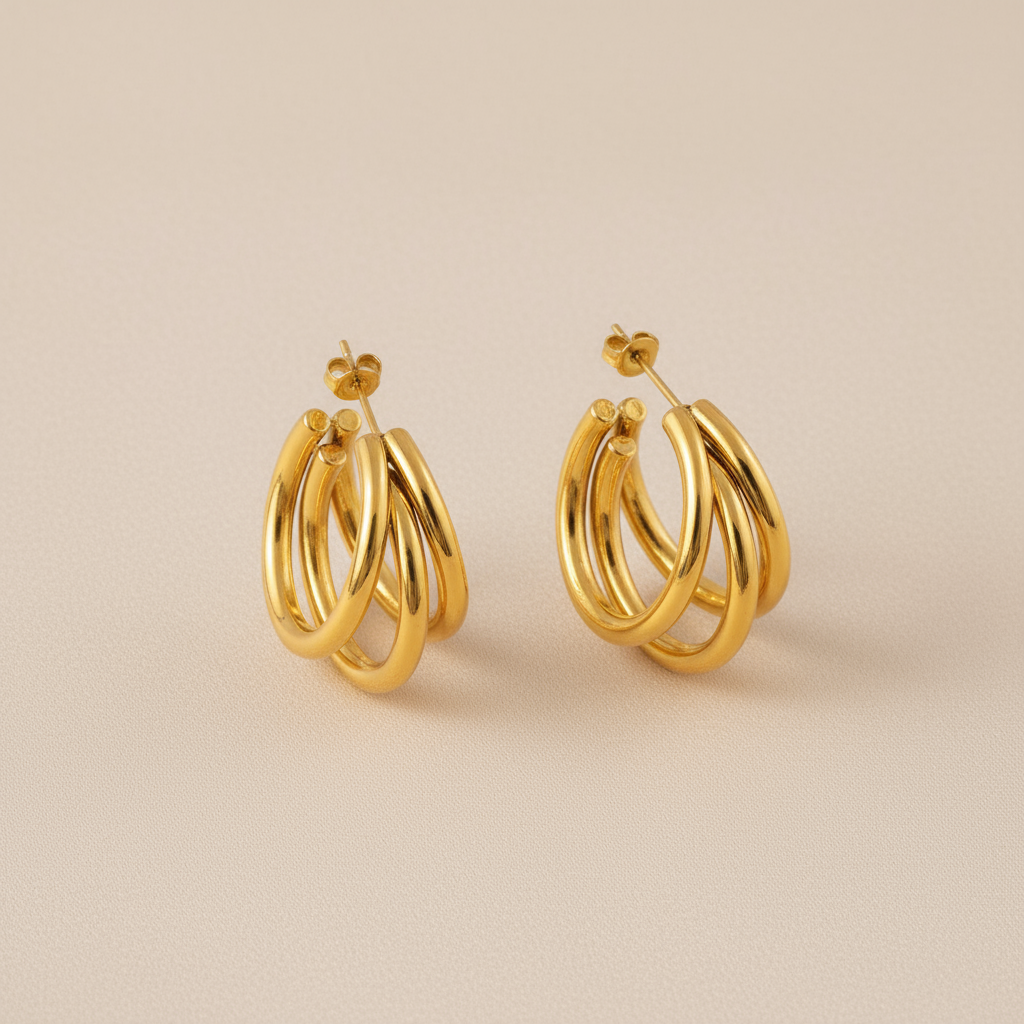 Pair of gold Triple Hoop Earrings on a beige background