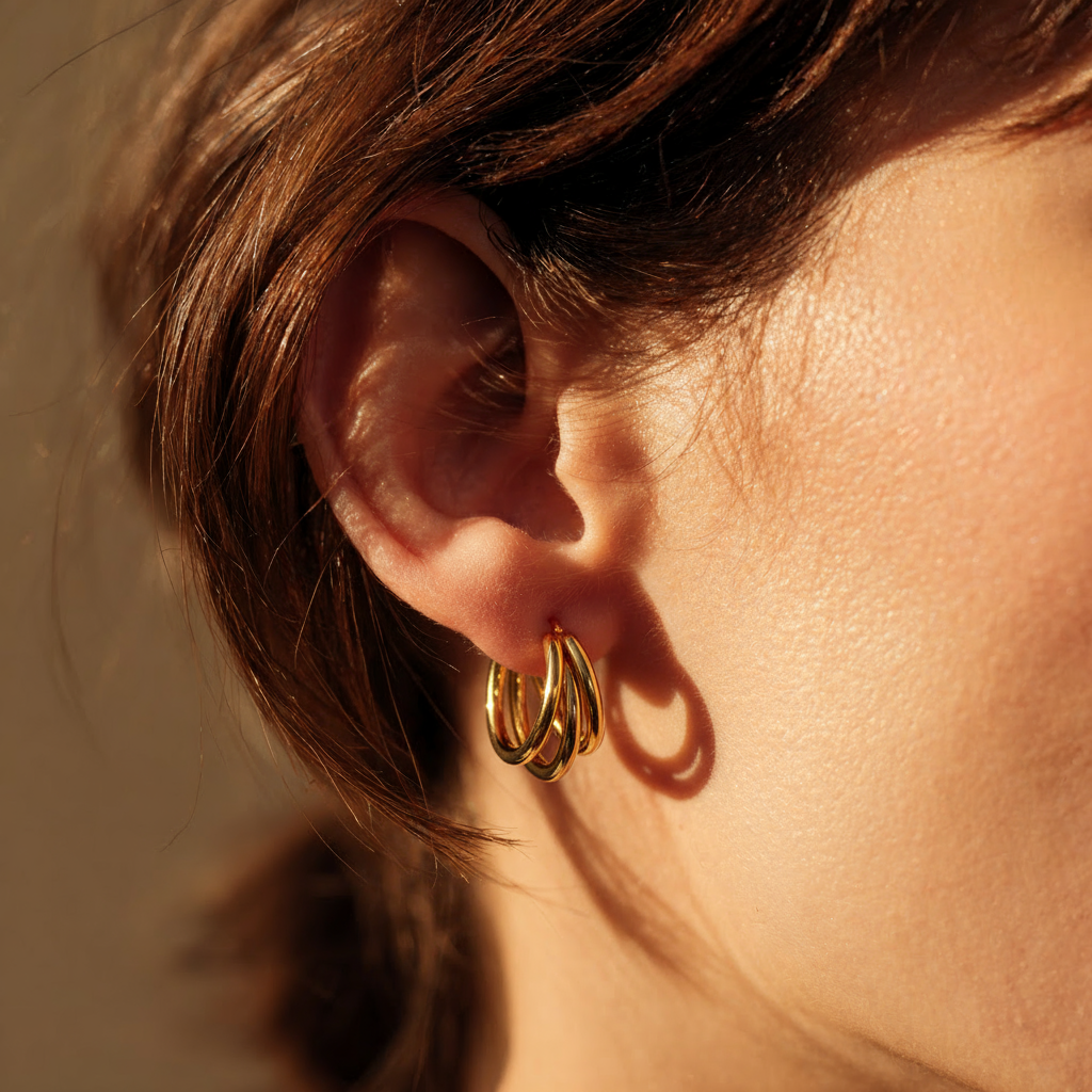 Close-up of an ear wearing a Triple Hoop Earring with a neutral background