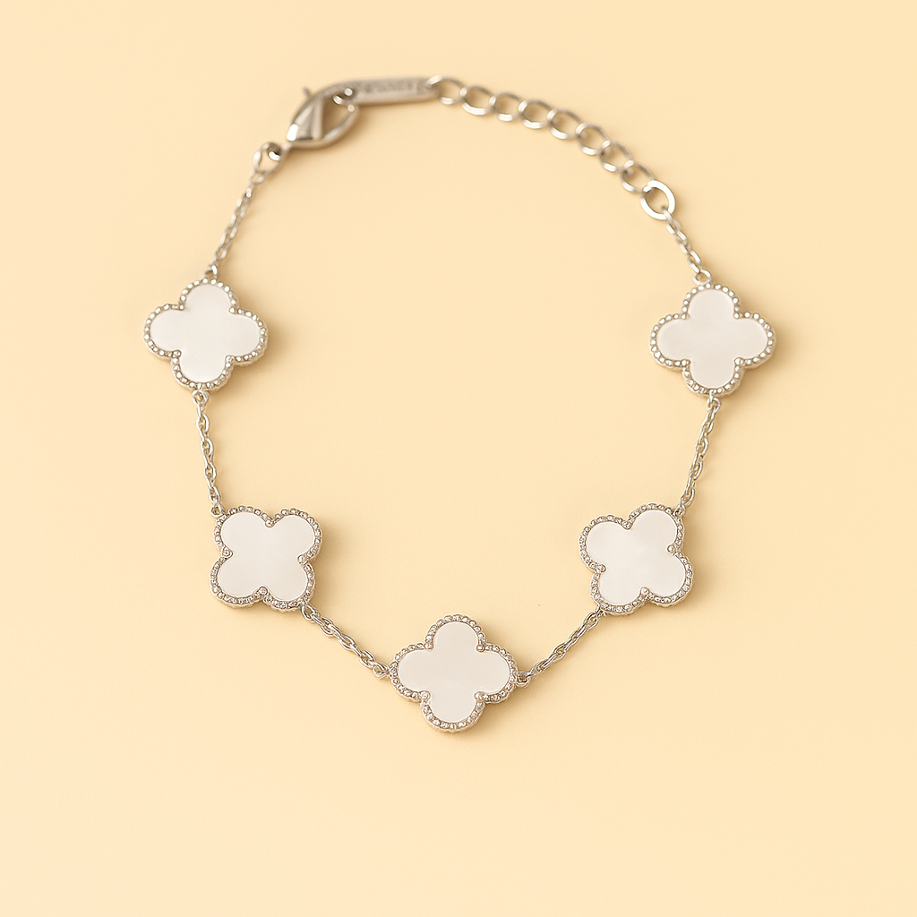 Silver bracelet with white clover-shaped charms on a beige background