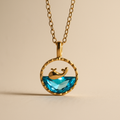 Gold necklace with a ocean pendant on a beige background