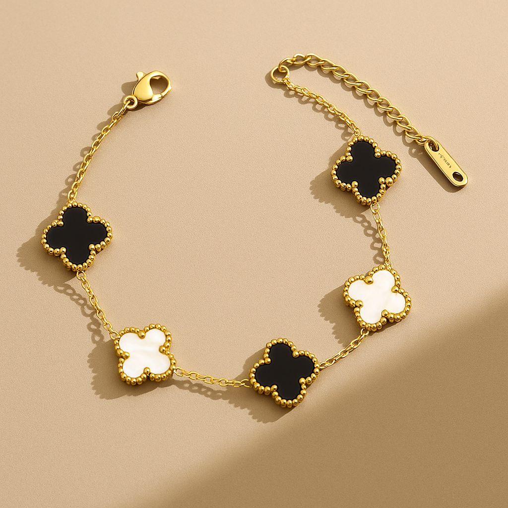 Gold bracelet with black and white clover-shaped charms on a beige background