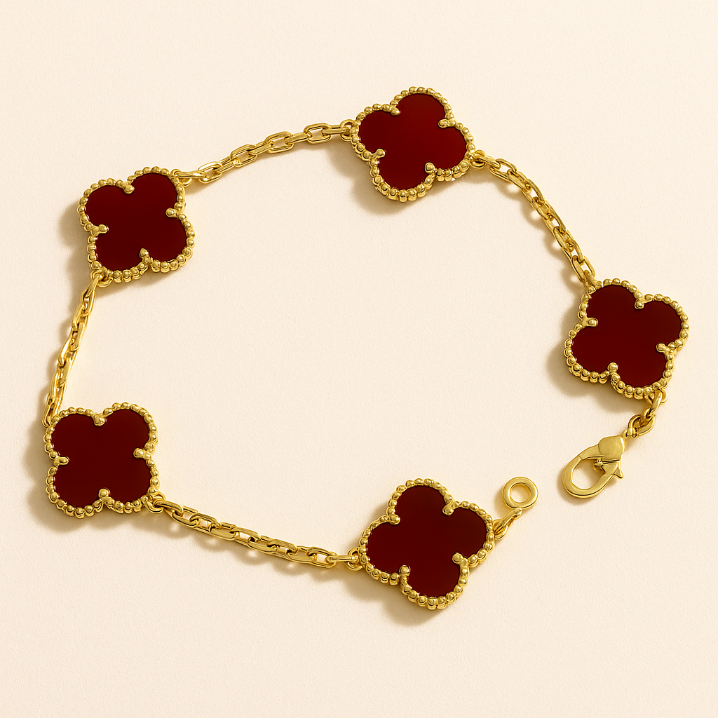 Gold bracelet with red clover-shaped charms on a beige background