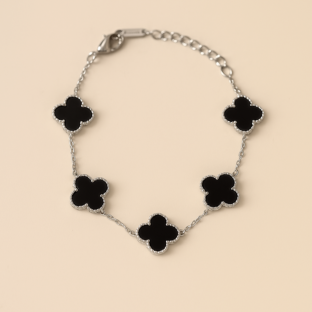 Silver bracelet with black clover-shaped charms on a beige background